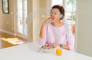 Young african american woman having healthy breakfast in the morning at home bored yawning tired covering mouth with hand