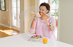 Young african american woman having healthy breakfast in the morning at home pointing fingers to camera with happy and funny face