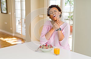 Young african american woman having healthy breakfast in the morning at home touching mouth with hand with painful expression