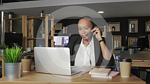 Young african american woman with headset talks to a customer while looking at her computer monitor.