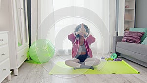 Young african american woman hippy in colourful sportswear with curly afro hairs sits in lotus pose and meditations