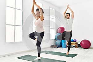 Young african american woman and hispanic man exercising at pilates room, stretching body and doing yoga pose, training strength