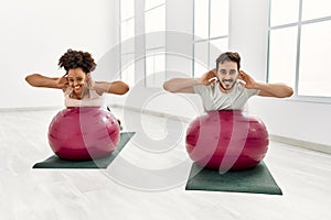 Young african american woman and hispanic man exercising at pilates room, stretching body and doing yoga pose, training strength