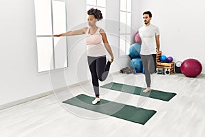 Young african american woman and hispanic man exercising at pilates room, stretching body and doing yoga pose, training strength