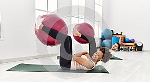 Young african american woman and hispanic man exercising at pilates room, stretching body and doing yoga pose, training strength