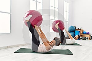 Young african american woman and hispanic man exercising at pilates room, stretching body and doing yoga pose, training strength