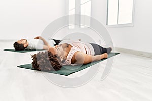 Young african american woman and hispanic man exercising at pilates room, stretching body and doing yoga pose, training strength