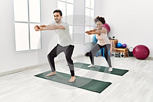 Young african american woman and hispanic man exercising at pilates room, stretching body and doing yoga pose, training strength