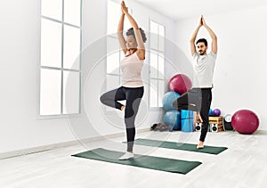 Young african american woman and hispanic man exercising at pilates room, stretching body and doing yoga pose, training strength