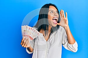 Young african american woman holding 10 colombian pesos banknotes shouting and screaming loud to side with hand on mouth