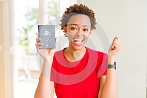 Young african american woman holding Australian passport screaming proud and celebrating victory and success very excited,