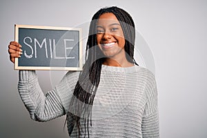 Young african american woman holding blackboard with smile word text over isolated background with a happy face standing and
