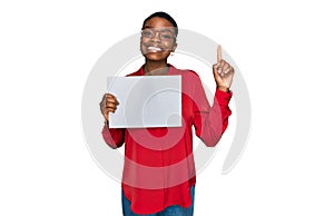 Young african american woman holding blank empty banner surprised with an idea or question pointing finger with happy face, number