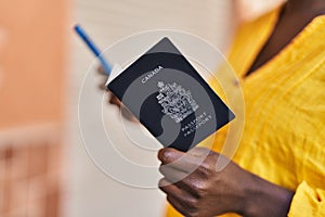 Young african american woman holding canada passport at street