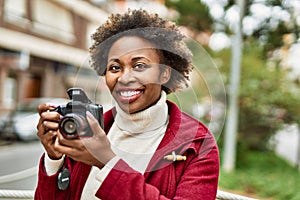 Young african american woman holding dslr camera at the city photo