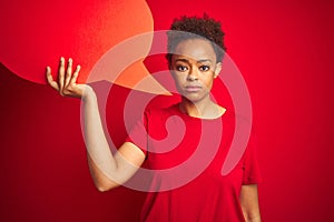 Young african american woman holding speech bubble over red isolated background with a confident expression on smart face thinking