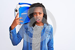 Young african american woman holding vintage retro radio over isolated background scared in shock with a surprise face, afraid and