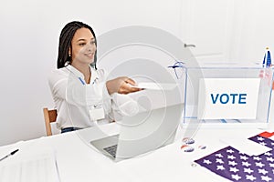 Young african american woman holding vote paper working at electoral college