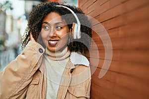 Young african american woman listening to music at the city