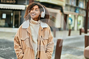 Young african american woman listening to music at the city