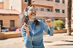 Young african american woman listening to music and dancing at park