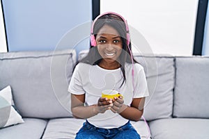 Young african american woman listening to music drinking coffee at home