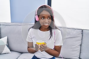 Young african american woman listening to music drinking coffee at home