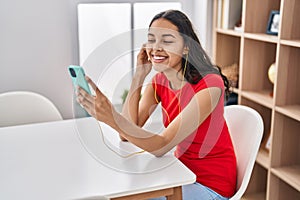 Young african american woman listening to music sitting on table at home