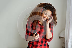 Young african american woman listening to music with smart phone and headphones