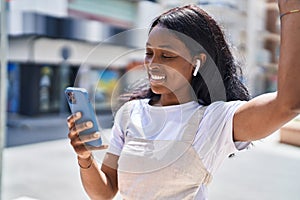 Young african american woman listening to music at street