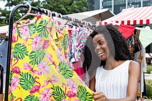 Young african american woman looking for new clothes at market