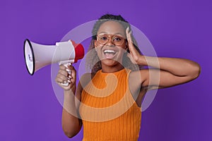 Young African American woman looks into camera with delight and holds megaphone