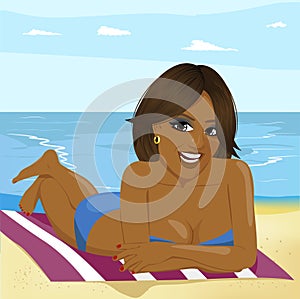 Young african american woman lying on towel on the beach