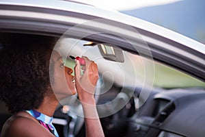 A young African-American woman makeup in the car