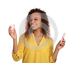 Young African American woman with menstrual cup and tampon on white background