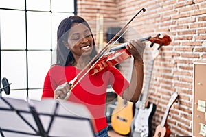 Young african american woman musician playing violin at music studio