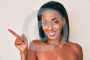 Young african american woman naked over background smiling happy pointing with hand and finger to the side