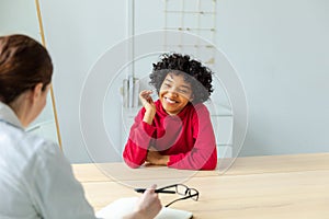 Young african american woman patient and female doctor in doctor office. Girl patient and doctor have consultation in