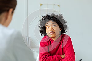 Young african american woman patient and female doctor in doctor office. Girl patient and doctor have consultation in