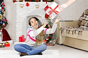 Young african american woman receive a Christmas gift. Happy excited dreaming girl about New Year presents. Christmas Eve, winter