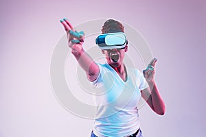 Young african-american woman`s using VR-glasses in neon light