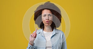 Young african american woman saying no with in dex finger gesture standing over orange studio background
