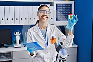 Young african american woman scientist analysing urine test tube using touchpad at laboratory