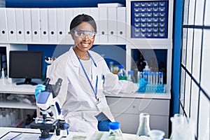 Young african american woman scientist using microscope working at laboratory