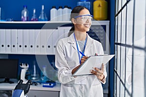 Young african american woman scientist write on report document at laboratory