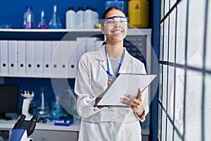 Young african american woman scientist write on report document at laboratory