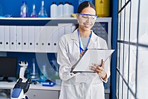 Young african american woman scientist write on report document at laboratory