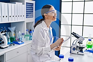 Young african american woman scientist write on report document at laboratory