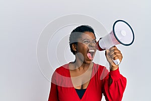 Young african american woman screaming angry using megaphone over isolated white background