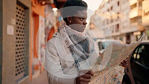 Young african american woman with serious expression holding city map at street